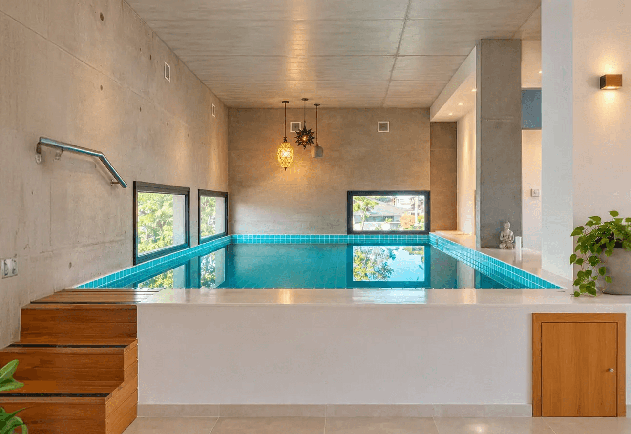 Piscina interior del spa con escalones de acceso y ventanas hacia el jardín