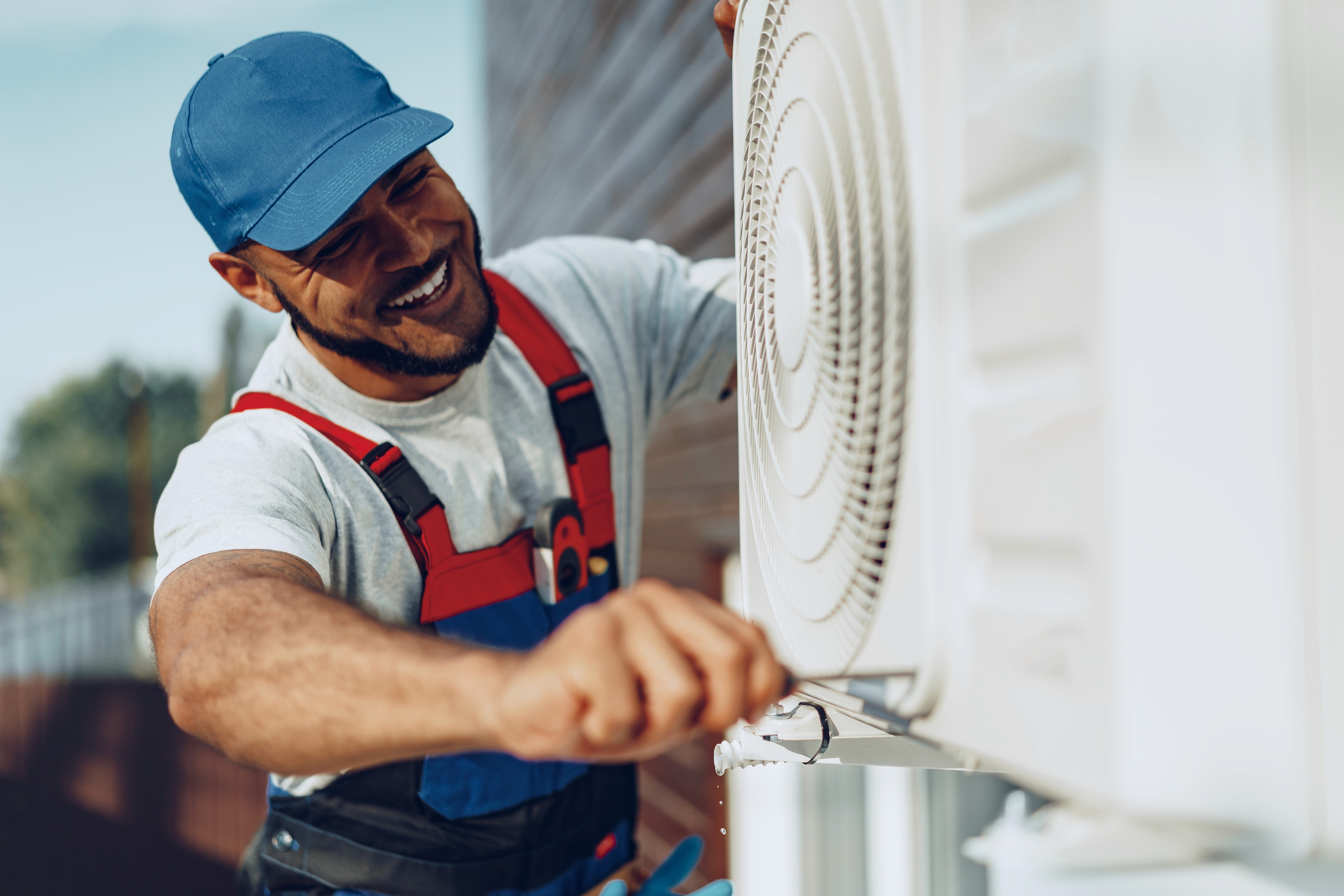Technician servicing an outdoor AC unit while wearing a safety harness