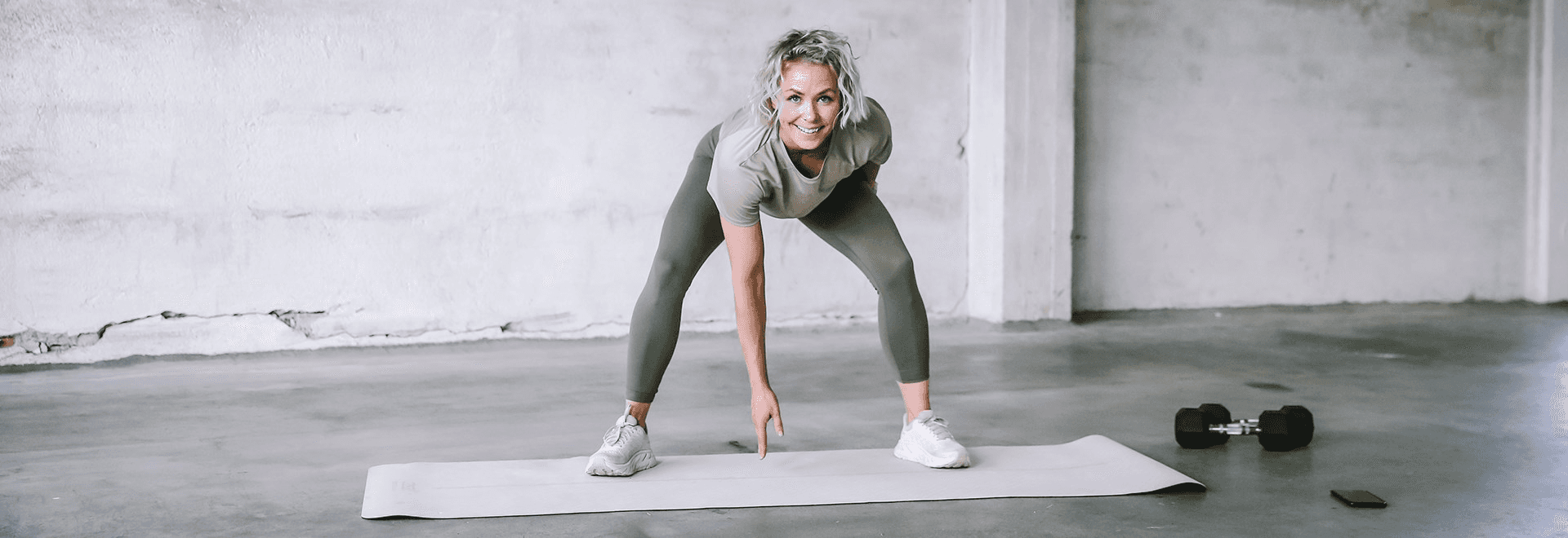 A person in activewear doing a workout on a mat in a bright, minimalistic gym space.