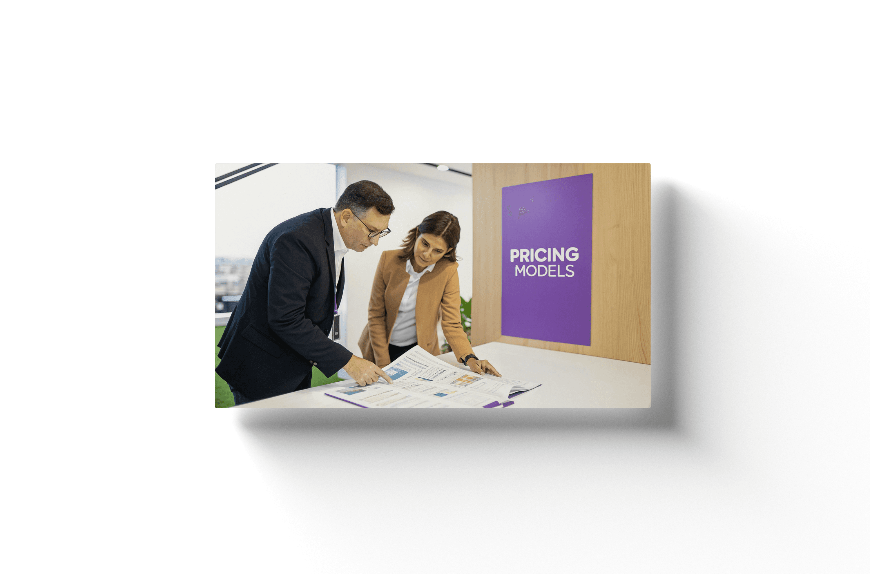 two people in an office setting analyzing a document on a desk with a wooden wall and purple banner displayin gthe text 'pricing models'