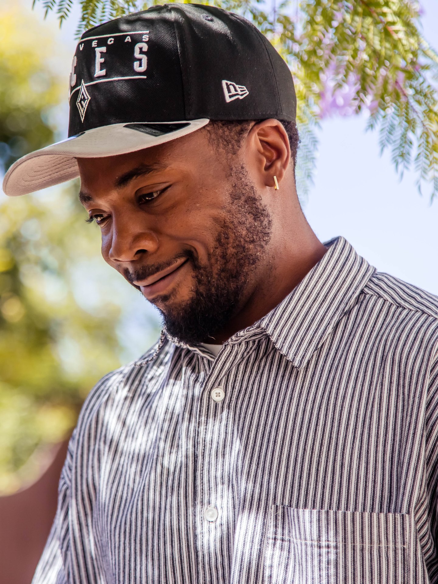 Smiling Knox teacher in a black cap and striped shirt standing outdoors