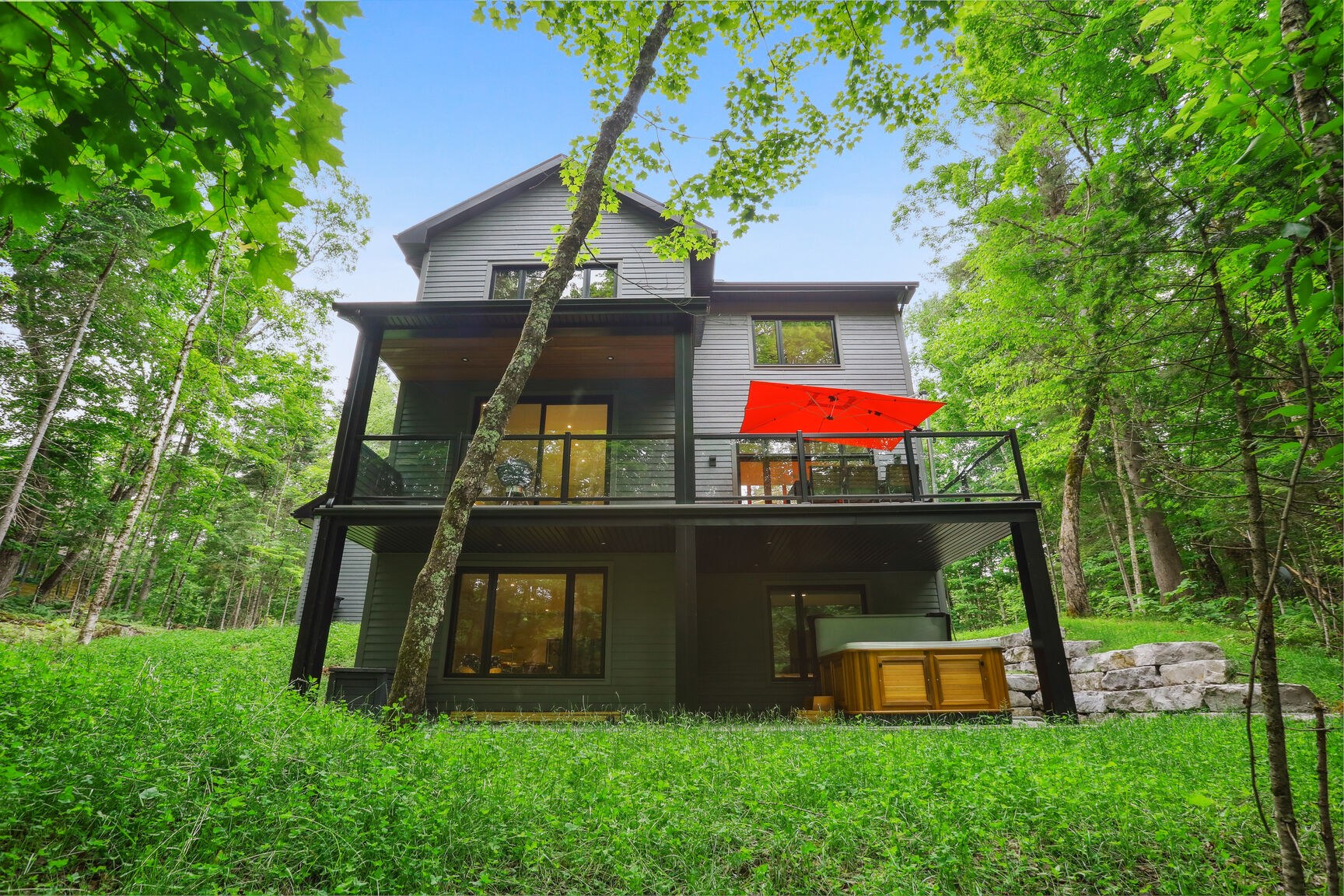 Façade arrière avec terrasse et garde-corps en verre.
