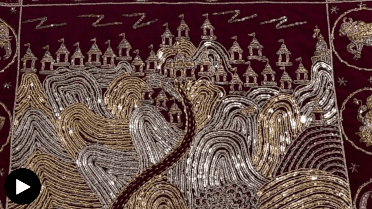 A red chod pata with golden and silver embroidery depicting a structure atop of mountains.