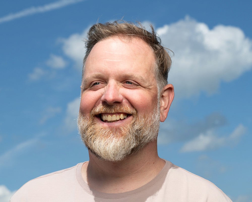 A silhouette of a person standing amidst vibrant swirling colors of teal and orange.