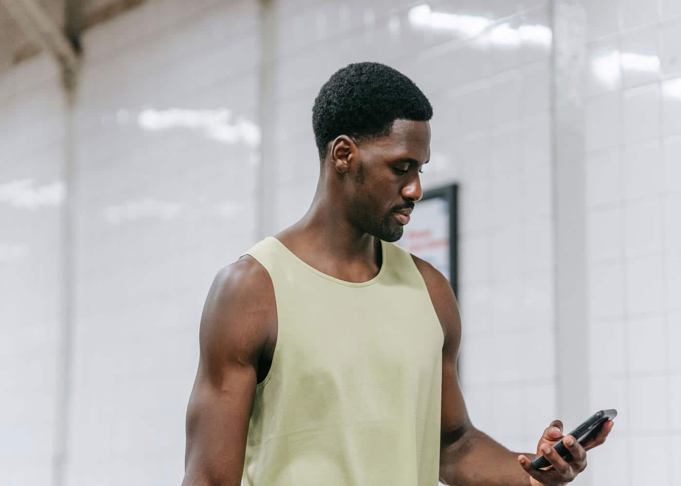 Man checking his bodybuilding app in-between workout sets