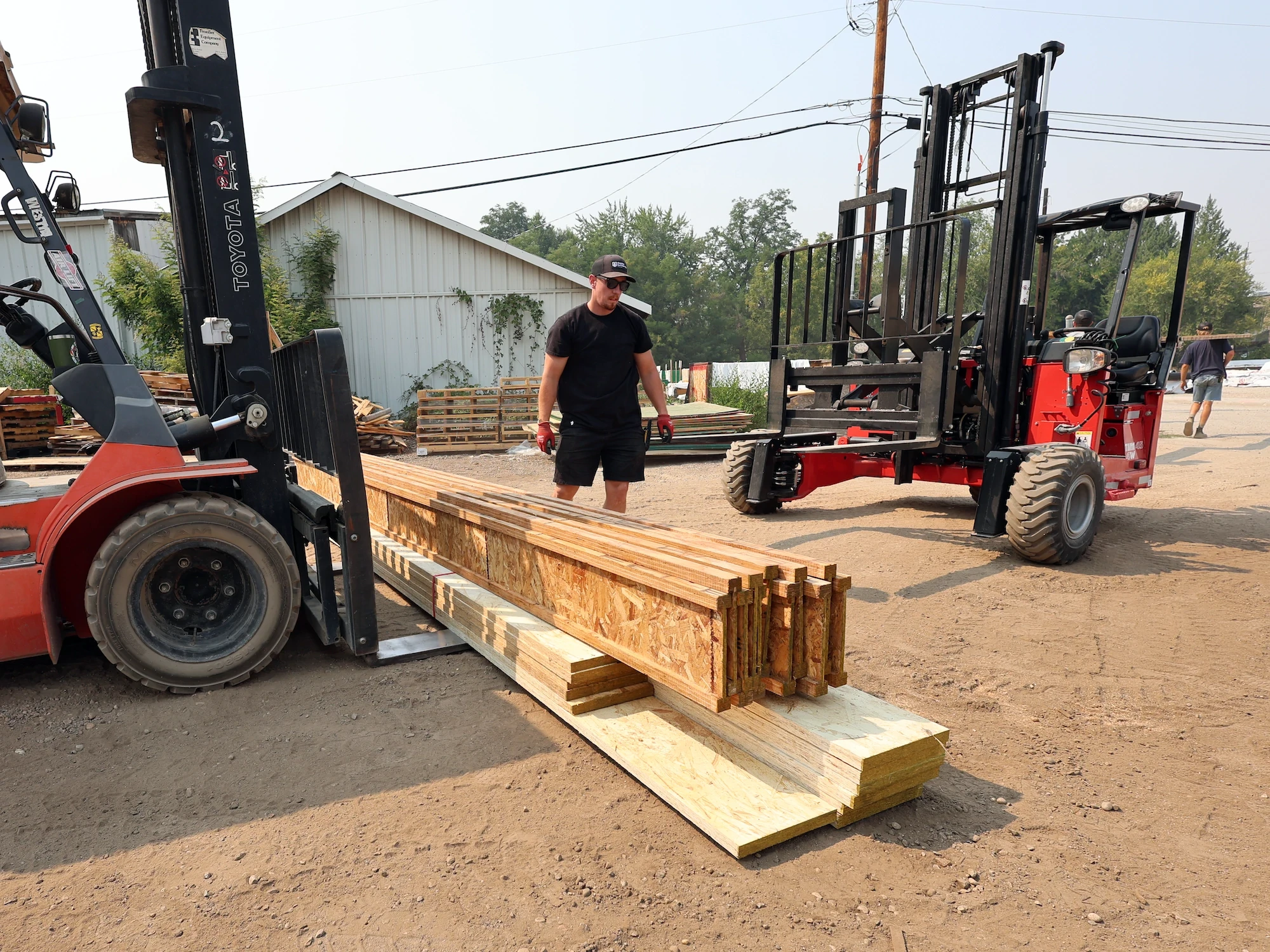 Capital Lumber team member working beside forklifts and stacked engineered lumber