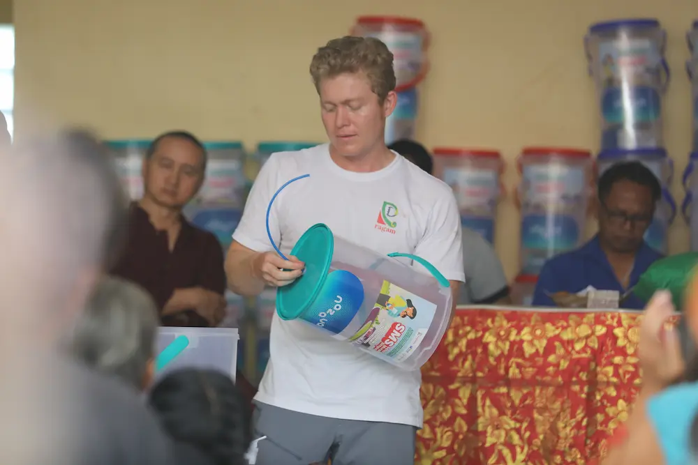 Young volunteer carries a water filter during a community distribution event in Bali.