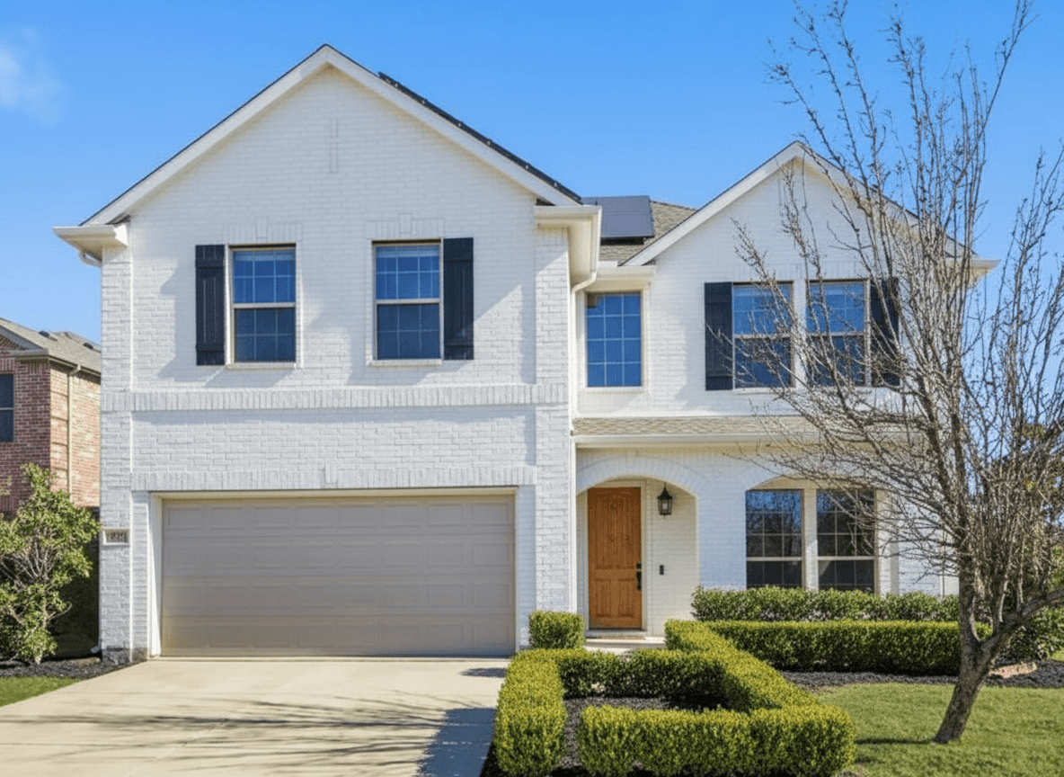 Same home remodeled with white painted brick, black window frames, warm wood door, and boxwood hedge landscaping