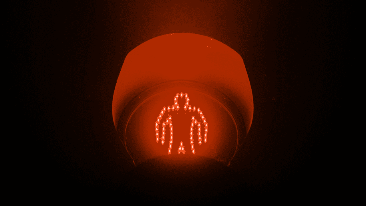 Orange glowing pedestrian signal showing a walking figure, indicating do not walk.
