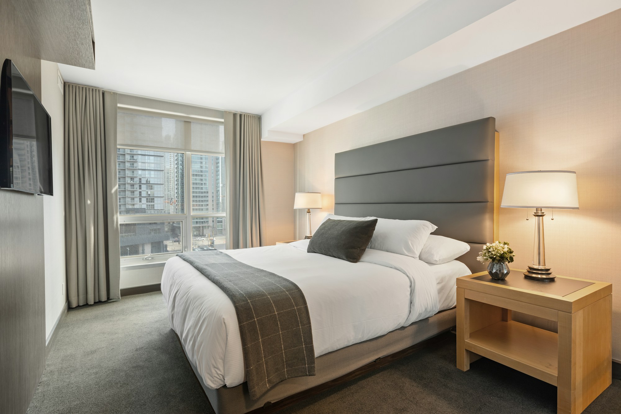 Bed dressed in white linen against a plastered wall