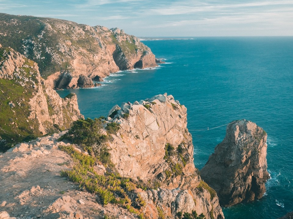 Fine art landscape photography of mountains by the sea coast with a woman practicing slackline