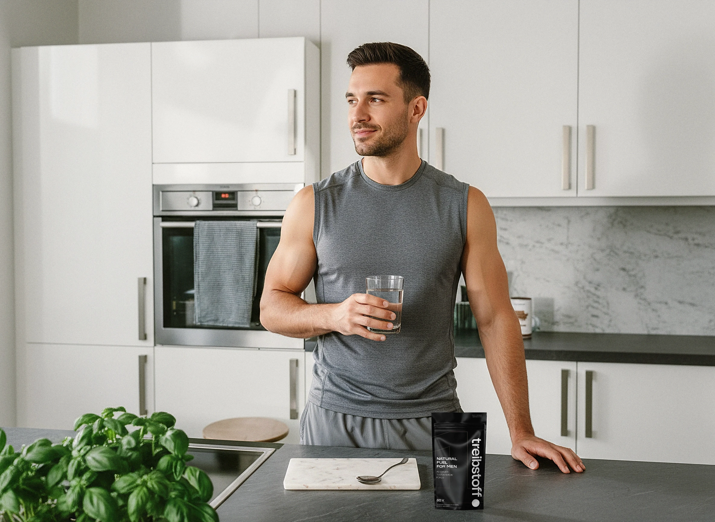 Mann in Sportkleidung trinkt Wasser in der Küche, daneben der treibstoff.-Doypack – visuelles Motiv für natürliche Supplementation im Alltag.