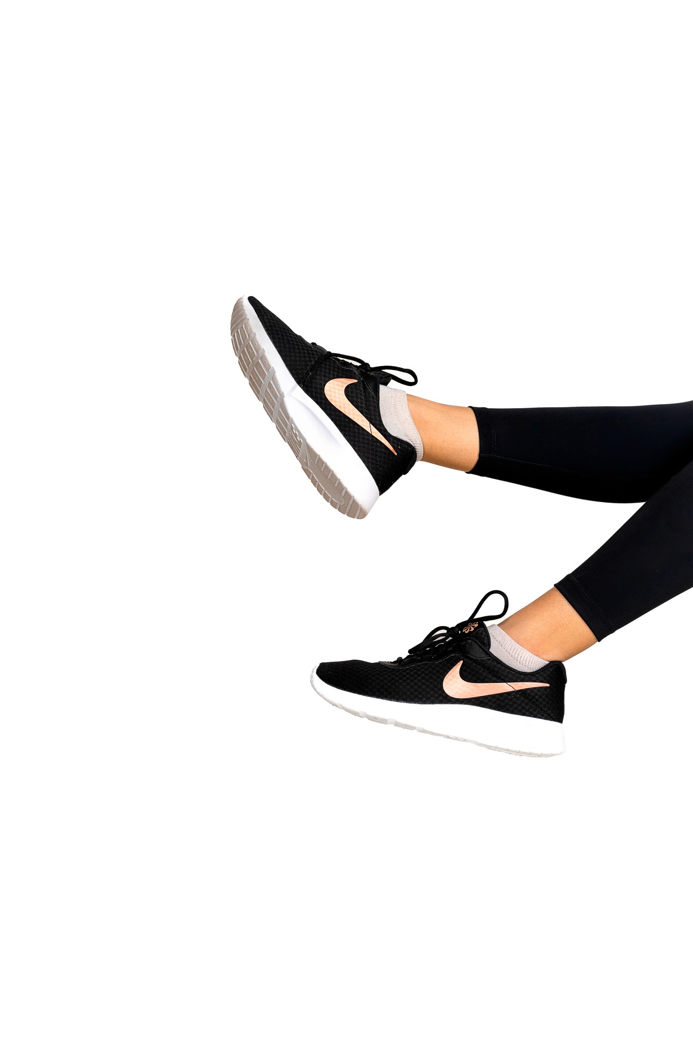 Nike shoes swining from off camera into frame on to a white wall.