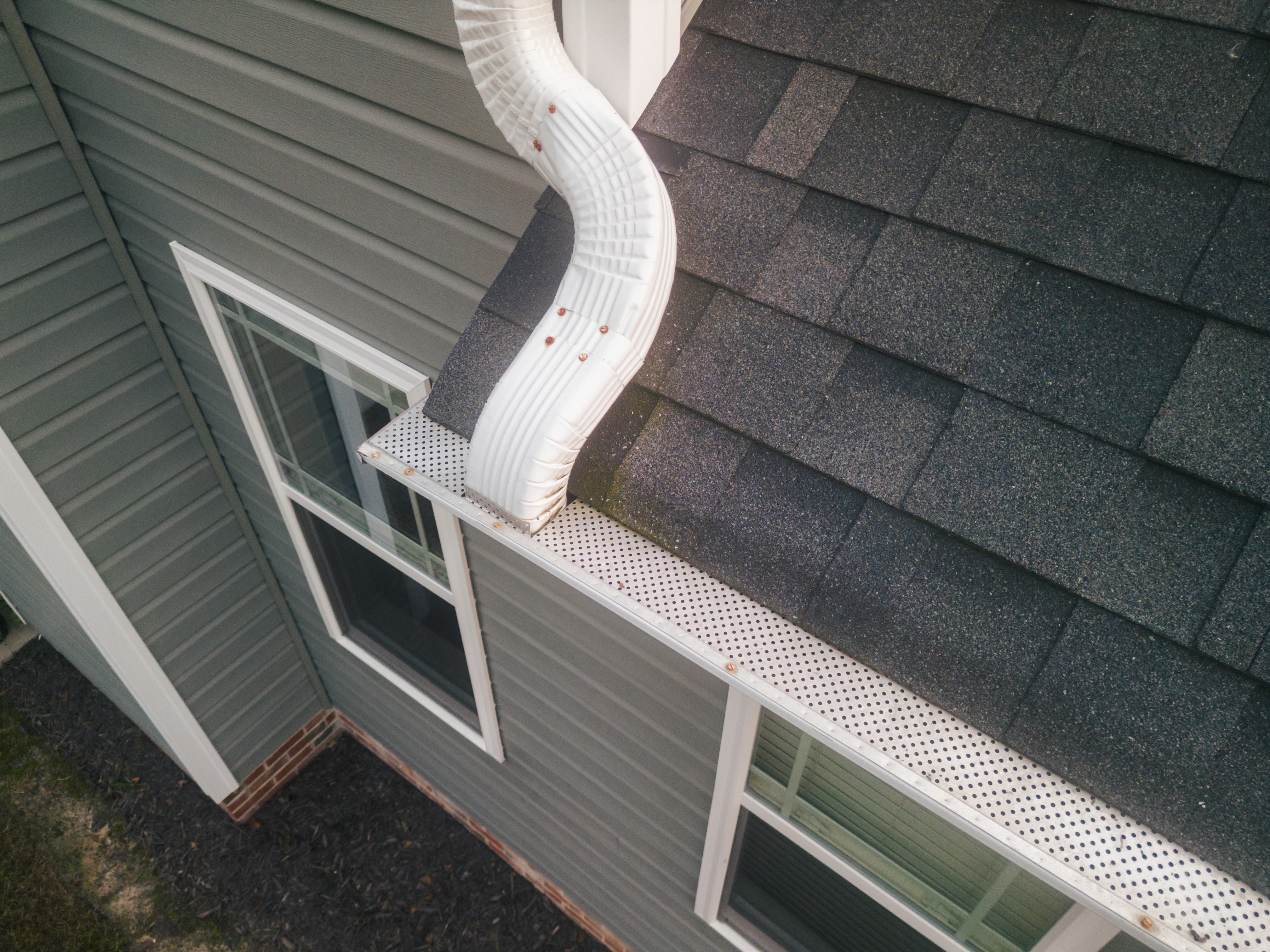 Residential home in Southern Indiana or Louisville neighborhood, recently completed roof visible (asphalt shingle, architectural or impact-resistant). Late-afternoon golden hour, neighborhood context, low off-axis angle. Lived-in, not staged.