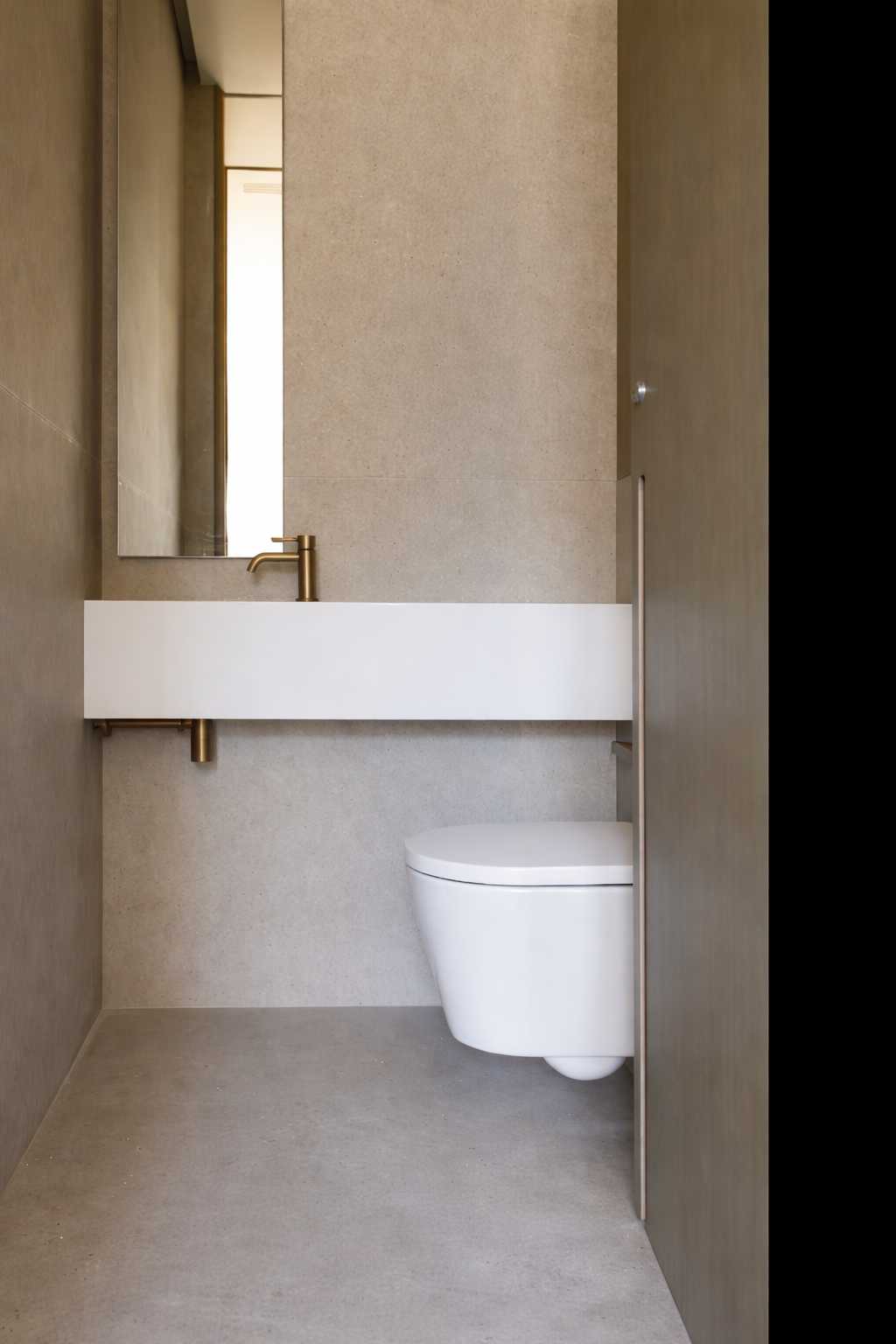 Toilettes avec lavabo suspendu blanc, miroir, robinetterie doree et WC suspendu sur mur en pierre beige