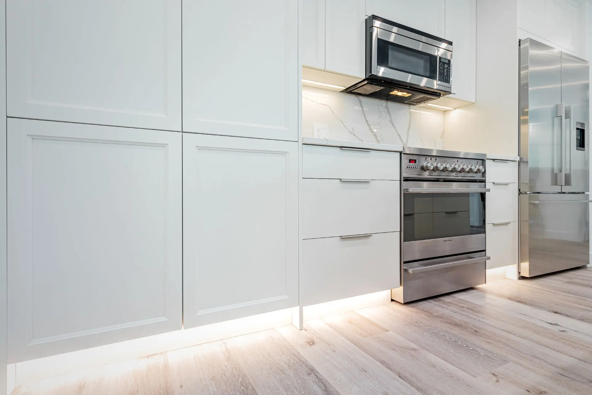 Modern white kitchen with black countertop and stainless steel hood