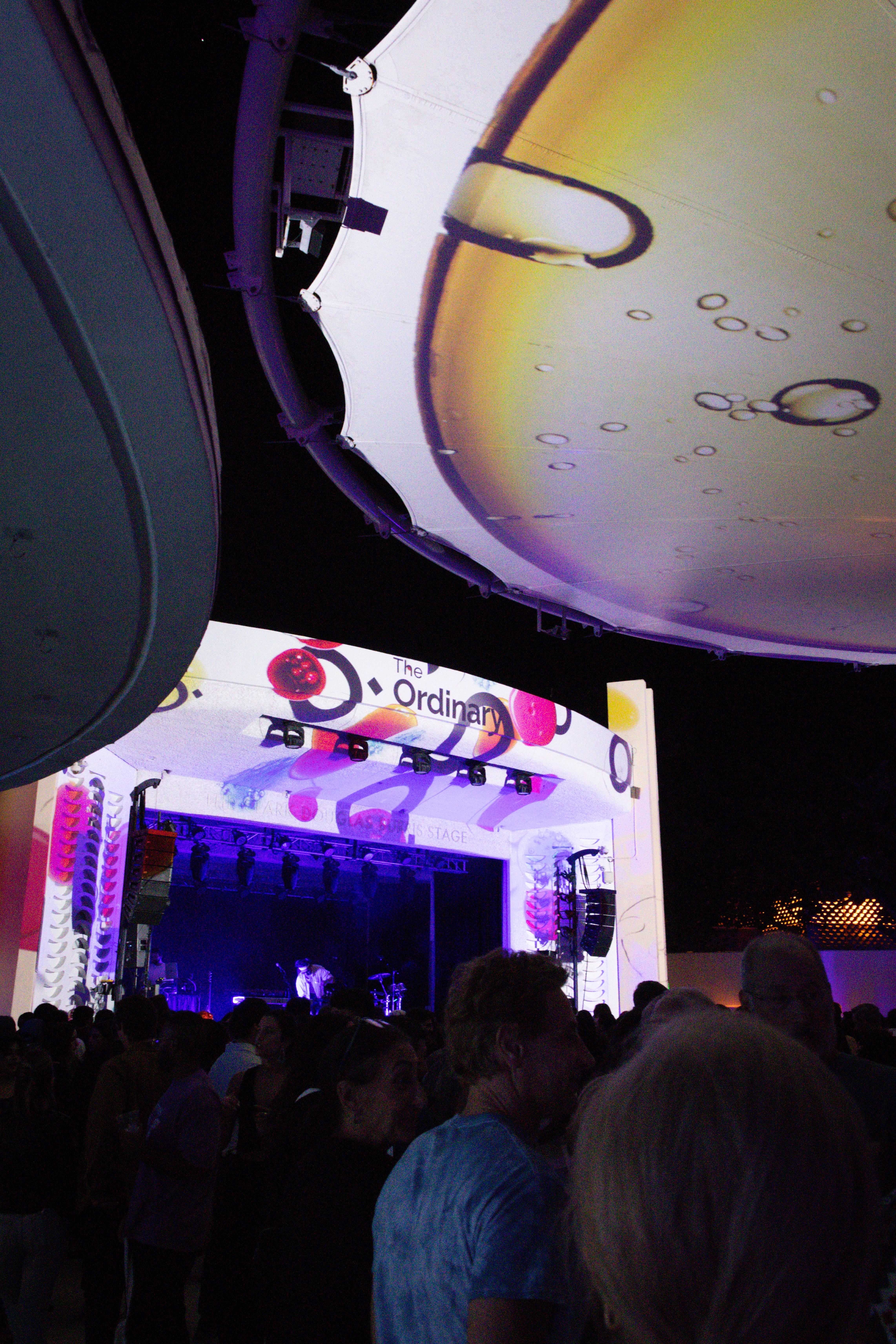 Large event crowd facing a lit stage during a nighttime festival performance.