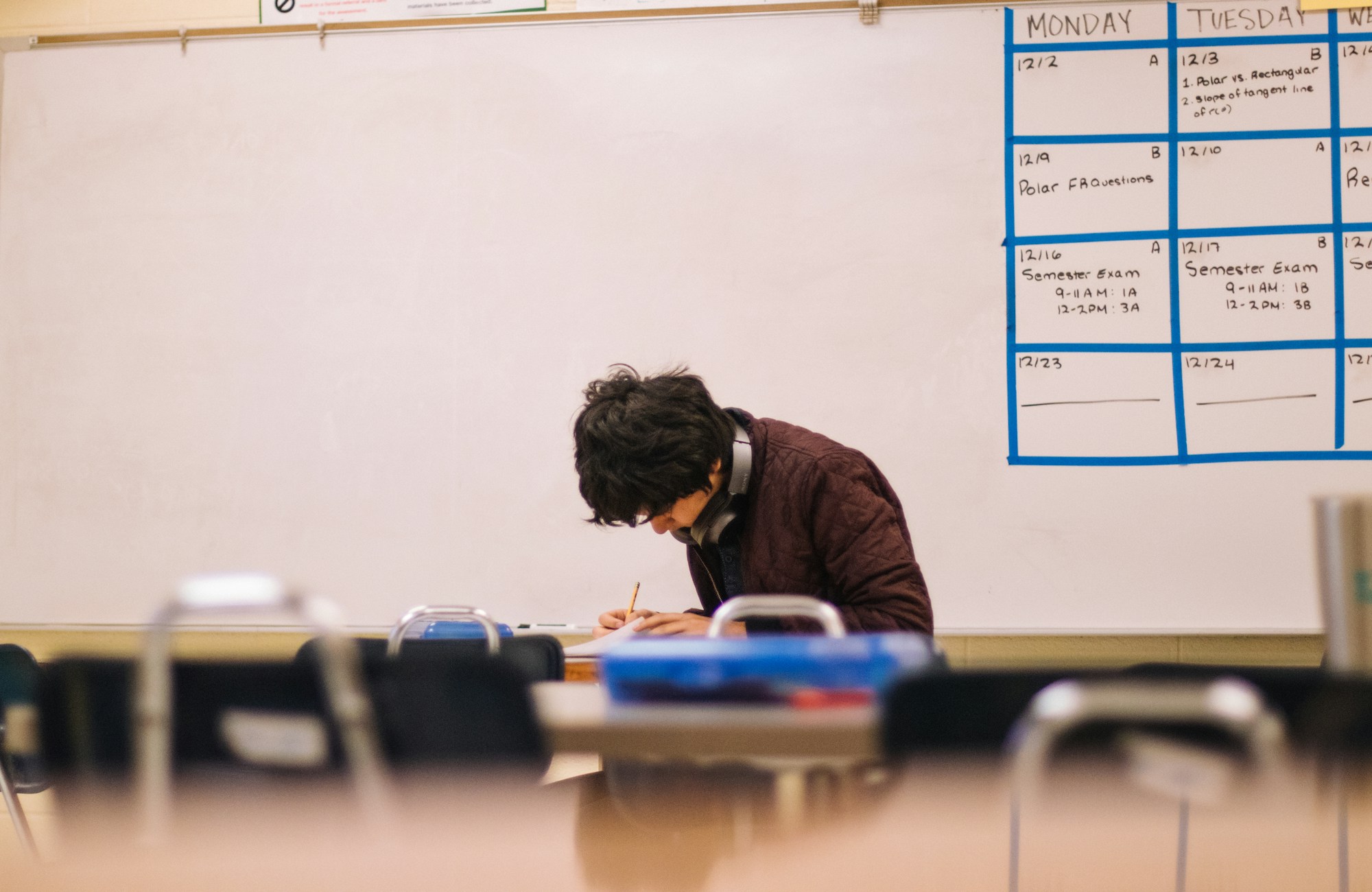 A student writing on paper at a classroom desk