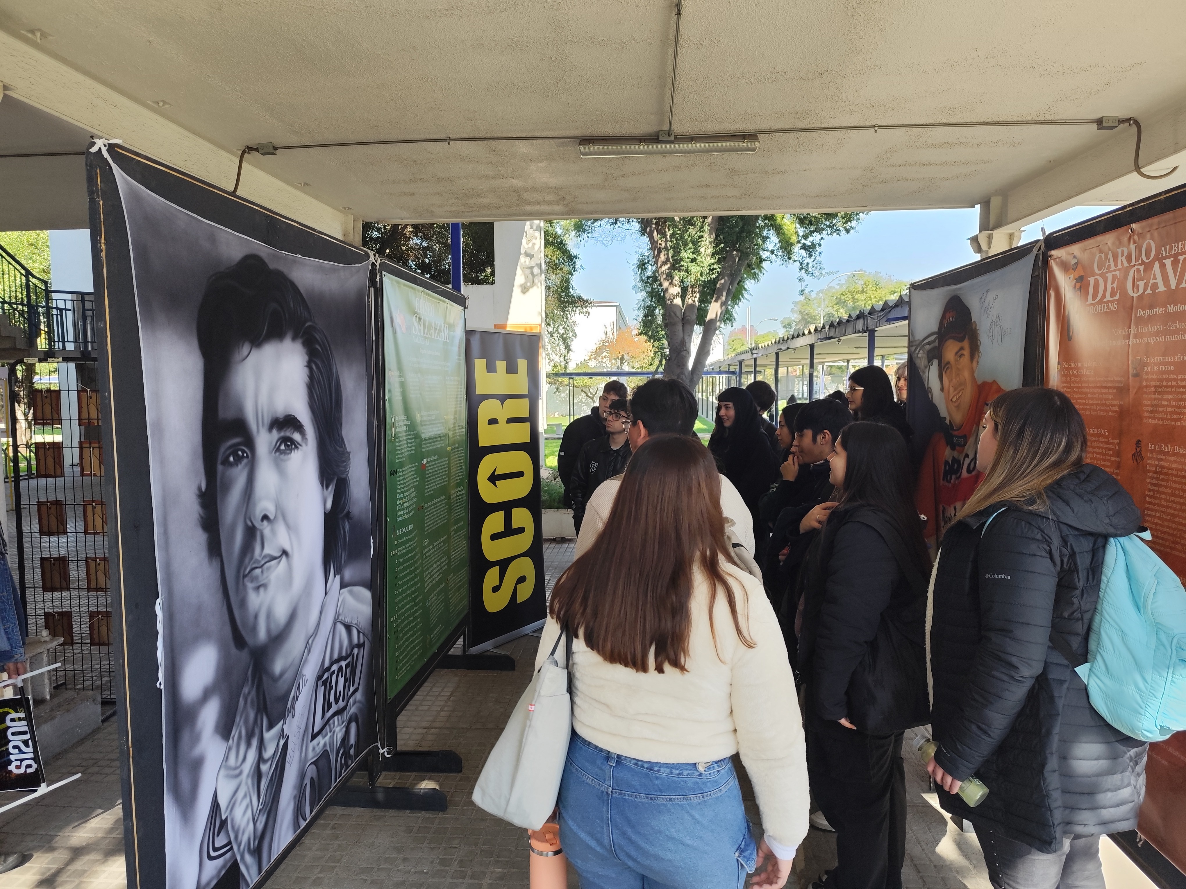 Asistentes observando la pintura de Eliseo Salazar, piloto chileno, en la exposición Leyendas del Deporte en USACH.