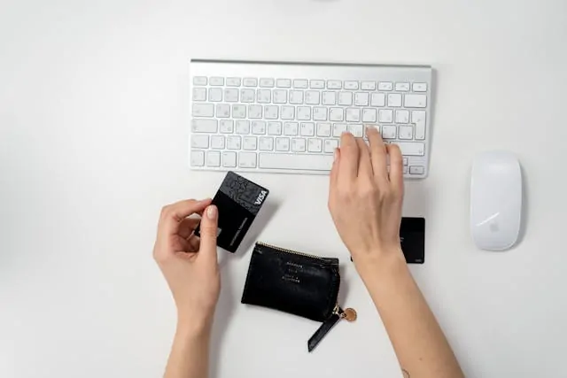 A hand holding a credit card to make an online payment