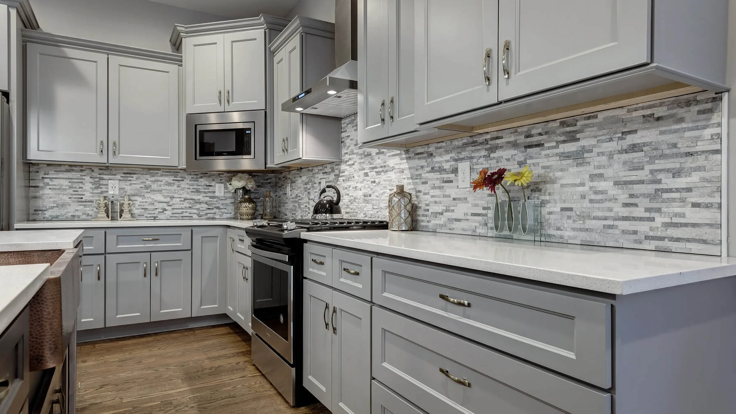 Gray shaker-style kitchen with a stone backsplash and quartz counters