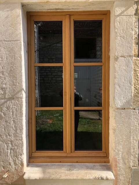 Détail de finition d'une fenêtre en bois massif, étanchéité et esthétique traditionnelle