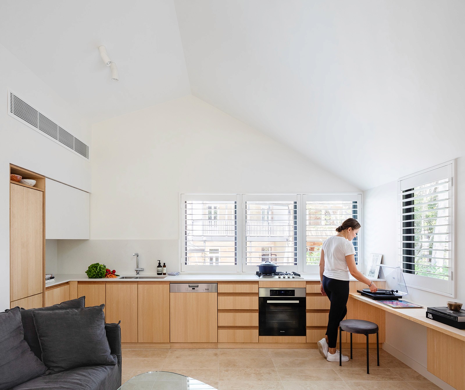 Light-filled kitchen and living space within the Woollahra Treehouse, featuring vaulted ceilings, timber joinery, and built-in seating oriented toward the garden.