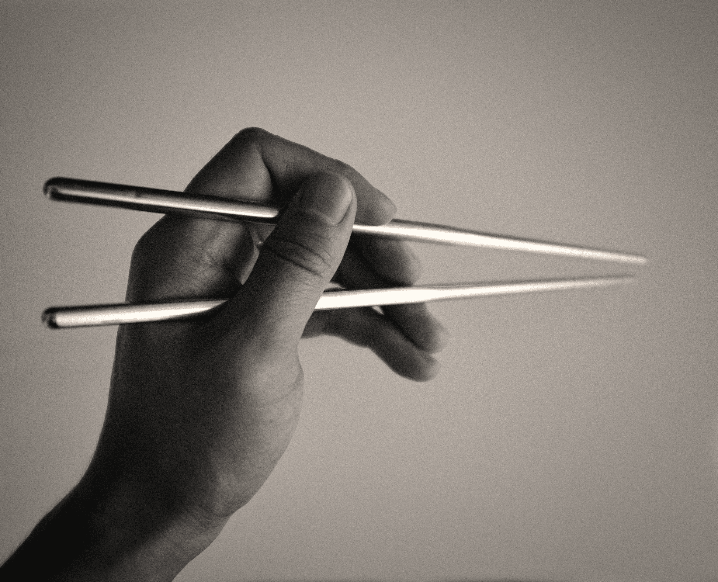 person holding sticks in grayscale photography