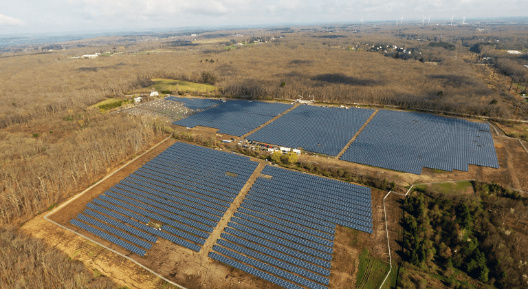 Aerial view of a solar panel array installed in a vast, open landscape with minimal vegetation.