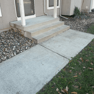 Clean concrete walkway and porch steps after professional pressure washing and surface restoration.