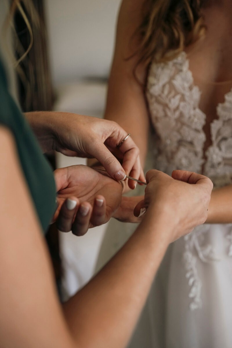 Bridesmaid helping bride fasten bracelet during wedding preparation