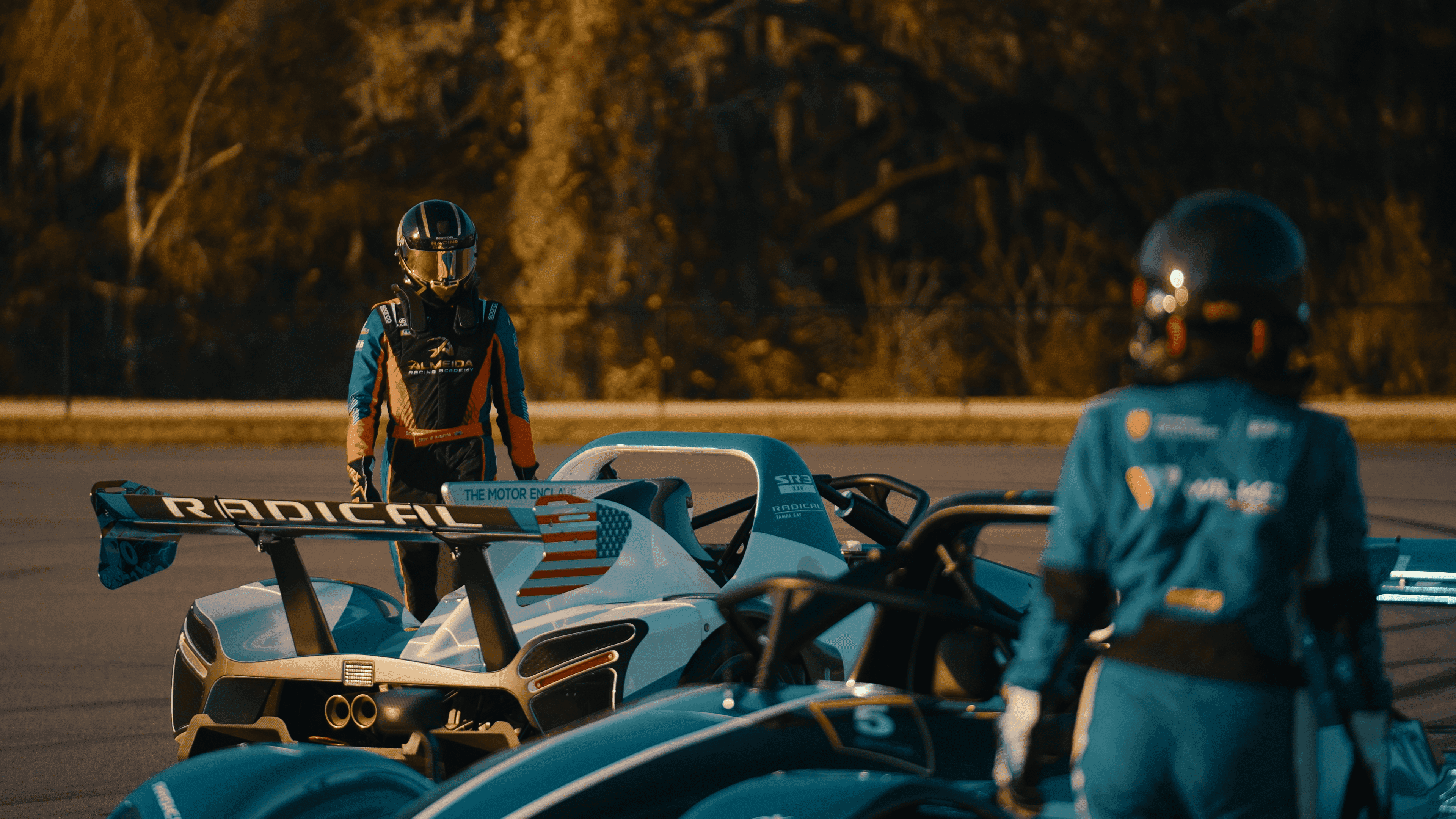 Suellio Almeida standing behind the SR10 race car during on-track driver training at Almeida Racing Academy.