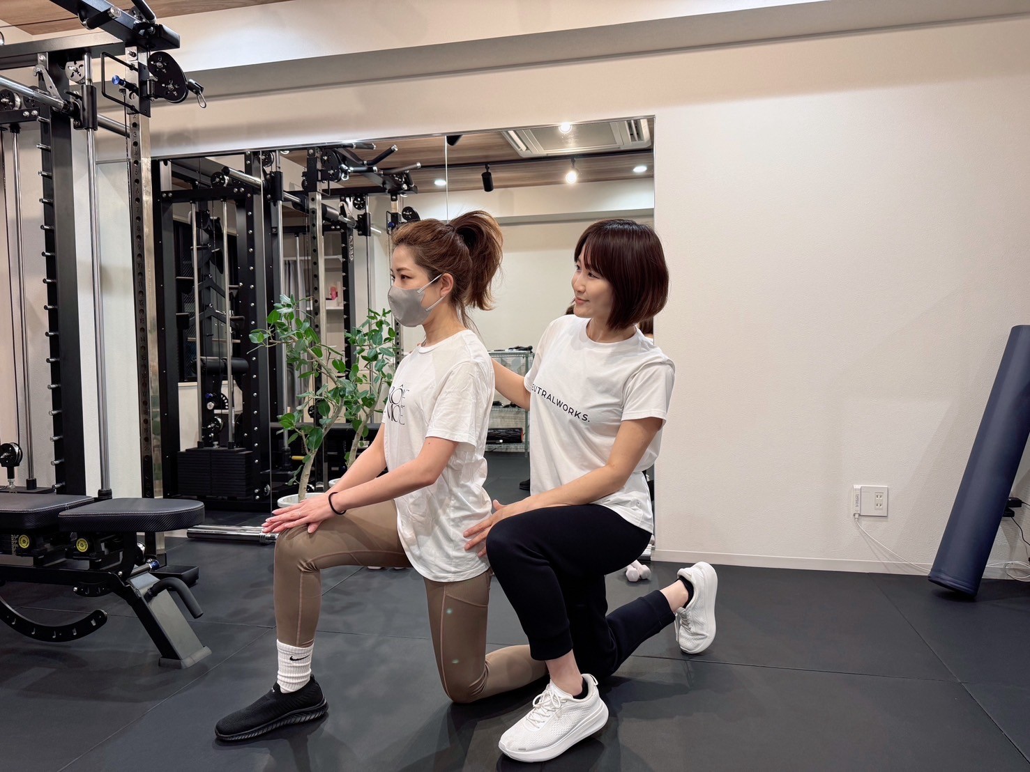 笑顔でダンベルトレーニングを指導するトレーナー