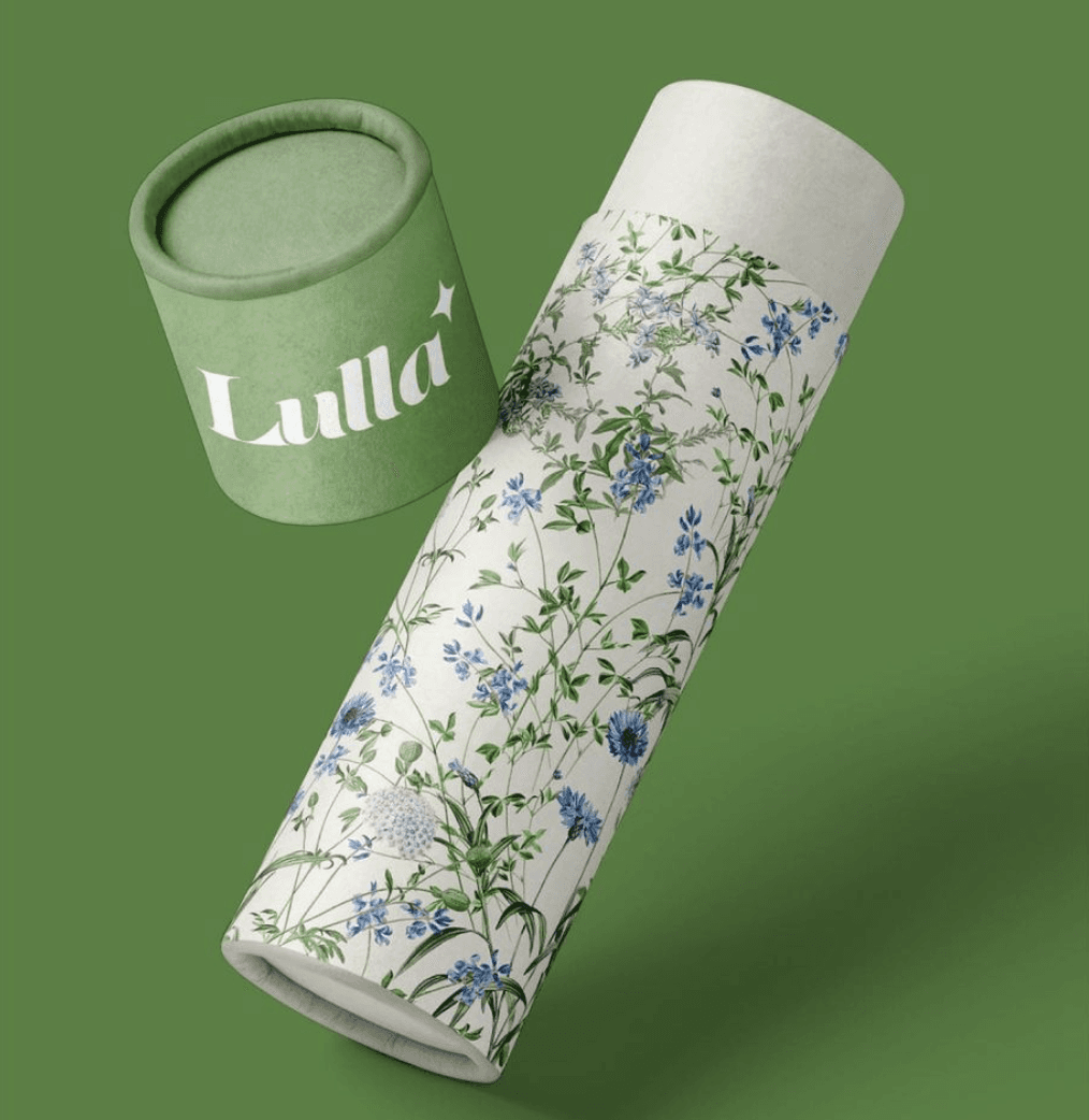 A decorative canister with a floral design next to a matching green lid on a green background.