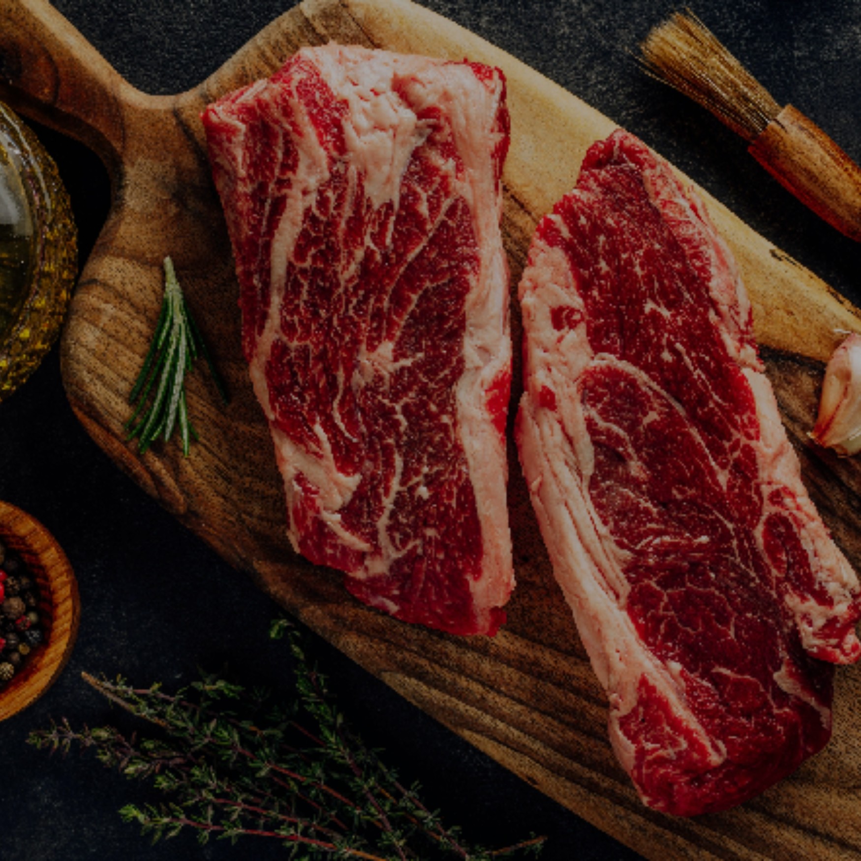 a slab of raw meat on a cutting board with vegetables and a bowl of sauce