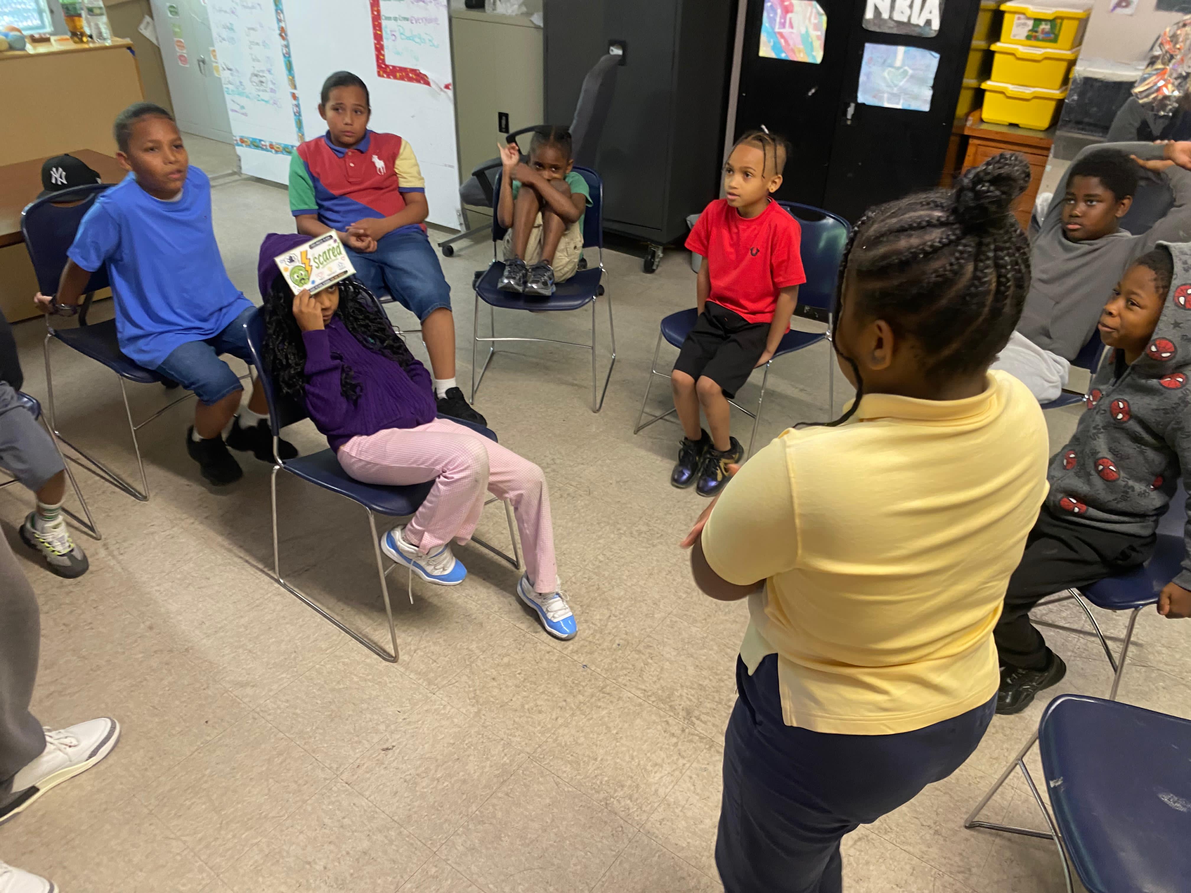 A student holds up a flashcard depicting the feeling 'Scared' during an educational presentation.