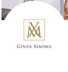 The image shows a logo with the text "Ginza Xiaoma" beneath a gold monogram design on a white background.