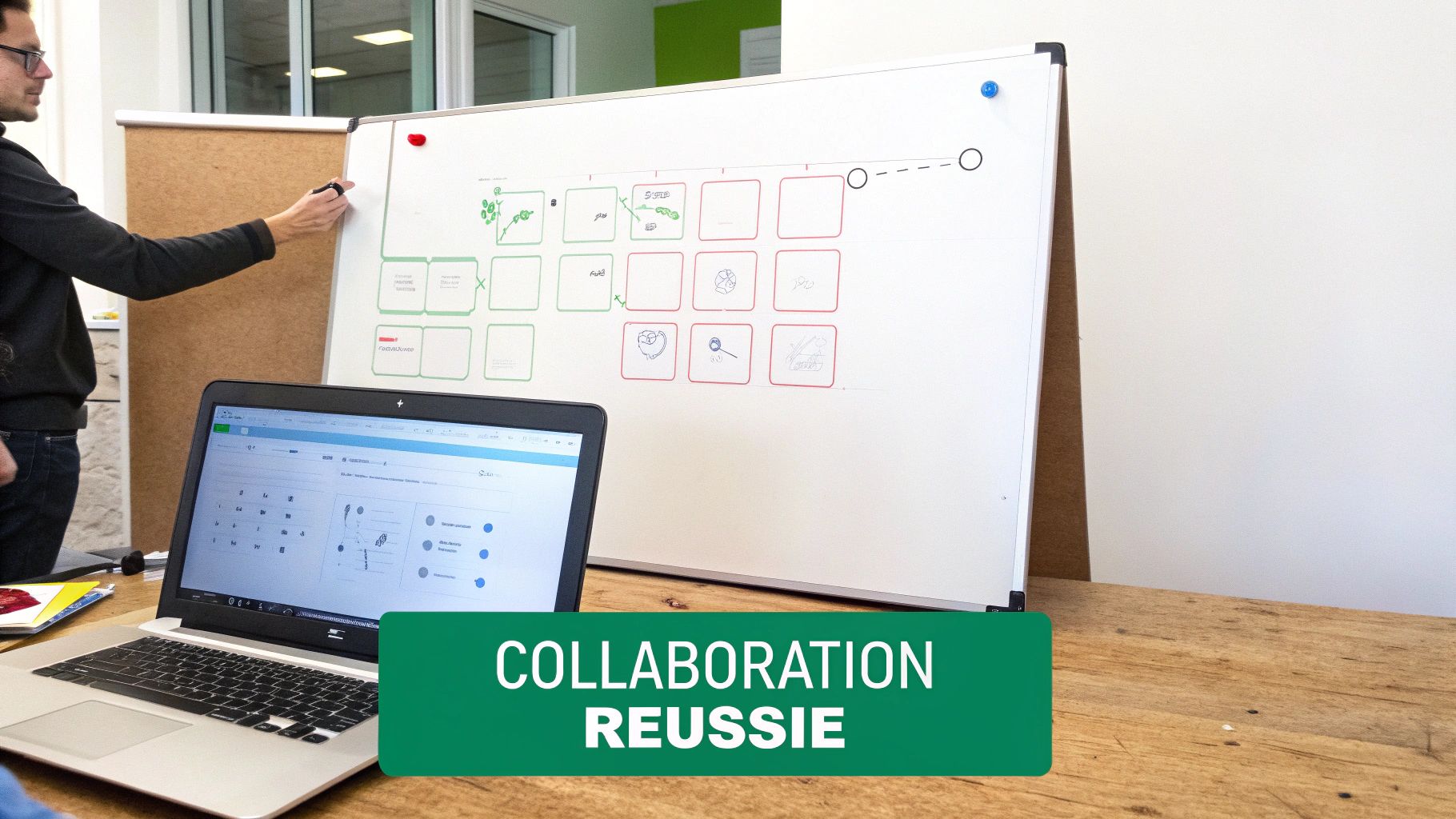 Personne écrivant sur un tableau blanc avec des diagrammes, un ordinateur portable ouvert sur une table en bois.