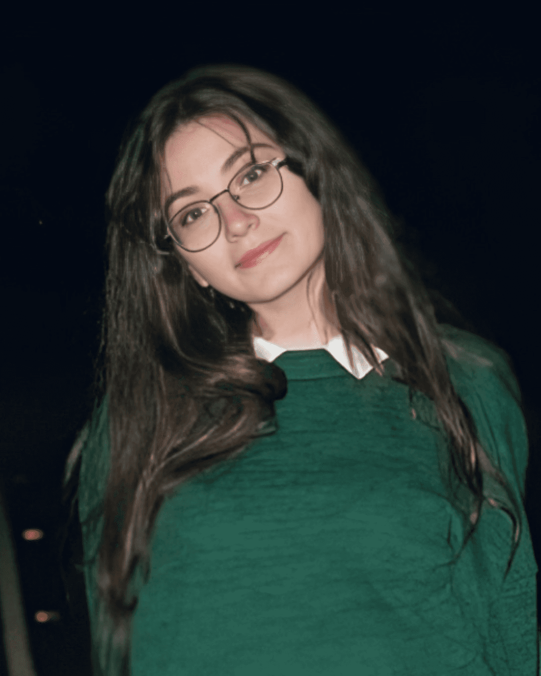 A young man with dark hair smiles at the camera, set against a modern indoor background.
