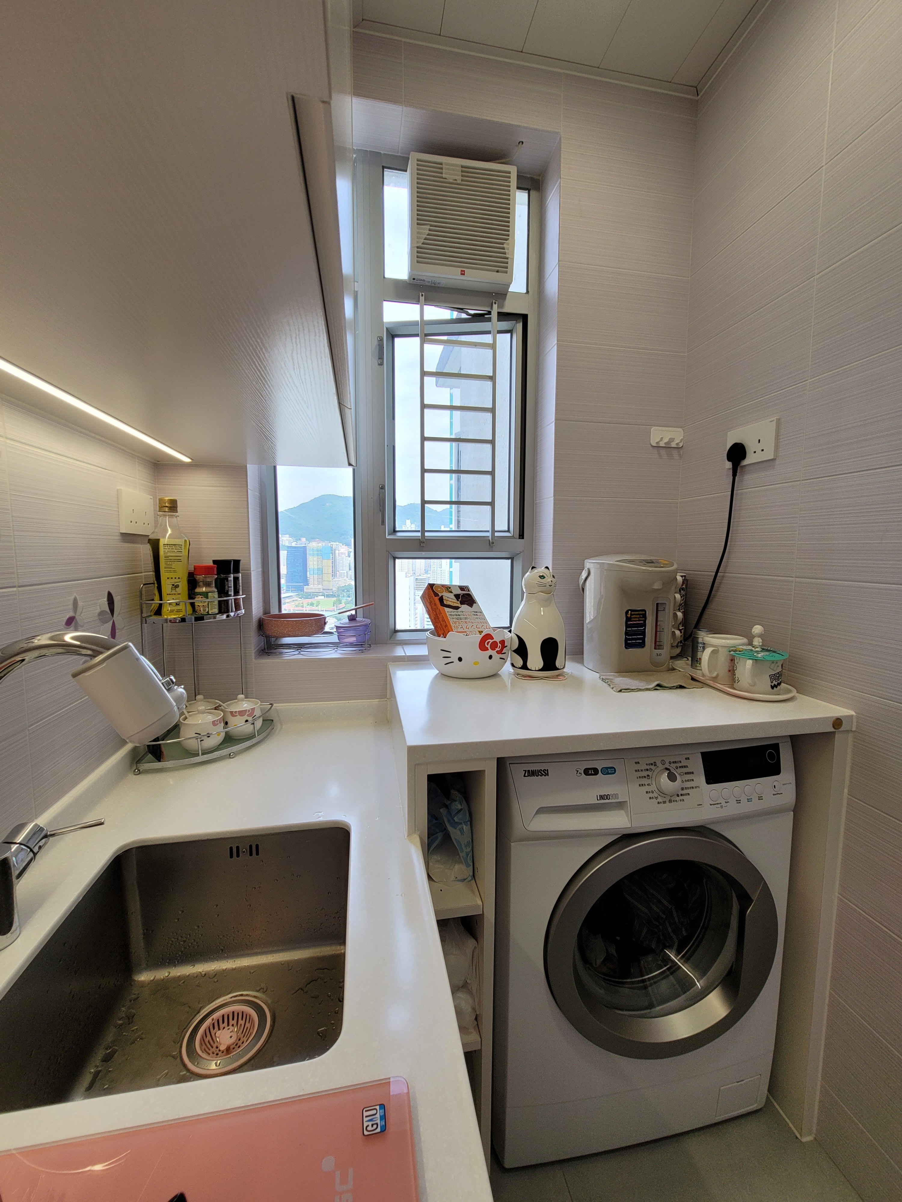 Natural light spills over the stainless steel sink and white quartz surfaces at Hoi Tat Estate, emphasizing the clean architectural layout.