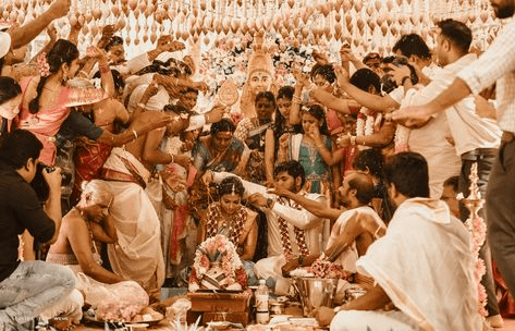 Detailed shot of Hindu wedding ritual with bride and groom’s hands united in an offering over the sacred fire, reflecting the spiritual aspect of wedding photography styles.