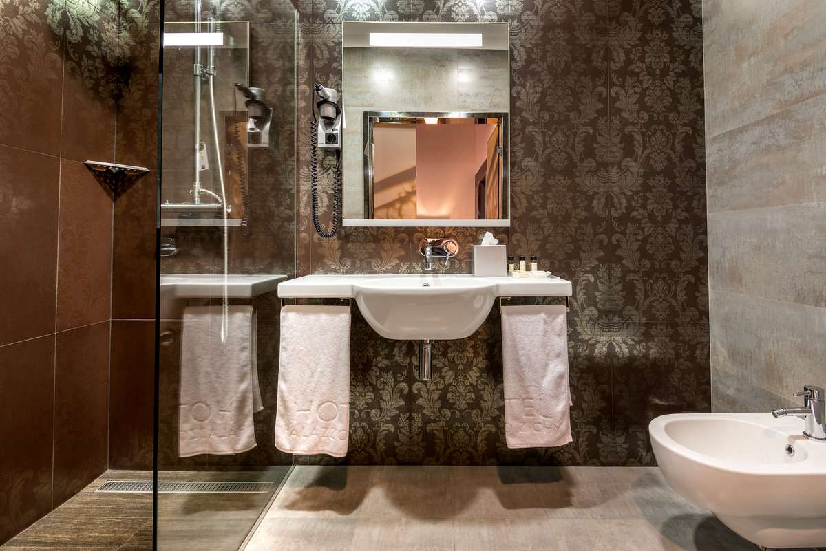 A modern bathroom features a glass shower stall, a marble-topped vanity with white towels, and a freestanding white soaking tub.