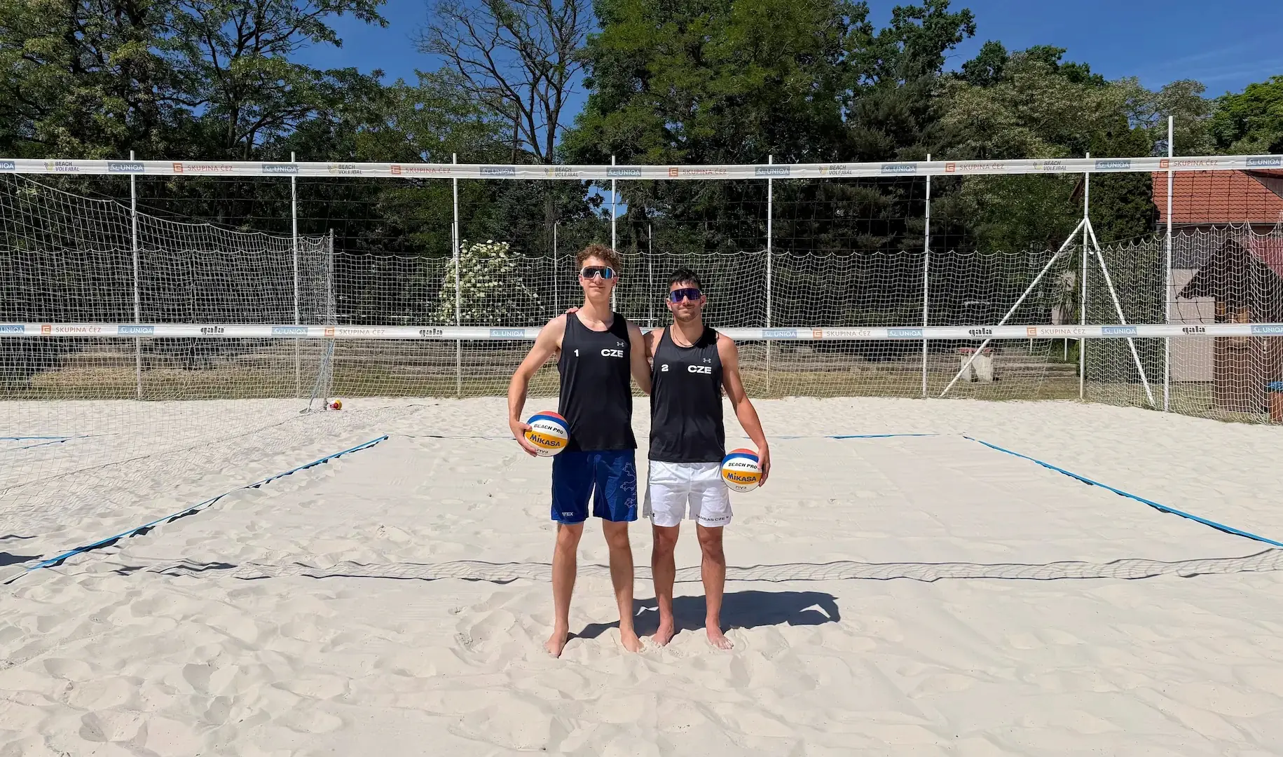 Tobiáš Nový a&nbsp;Šimon Bambas stojící při sobě na beachvolejbalovém kurtu v&nbsp;areálu Sportcentrum Koráb.