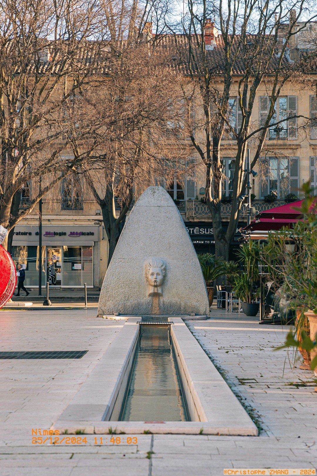 Fontaine moderne avec tête sculptée en pierre à Nîmes.