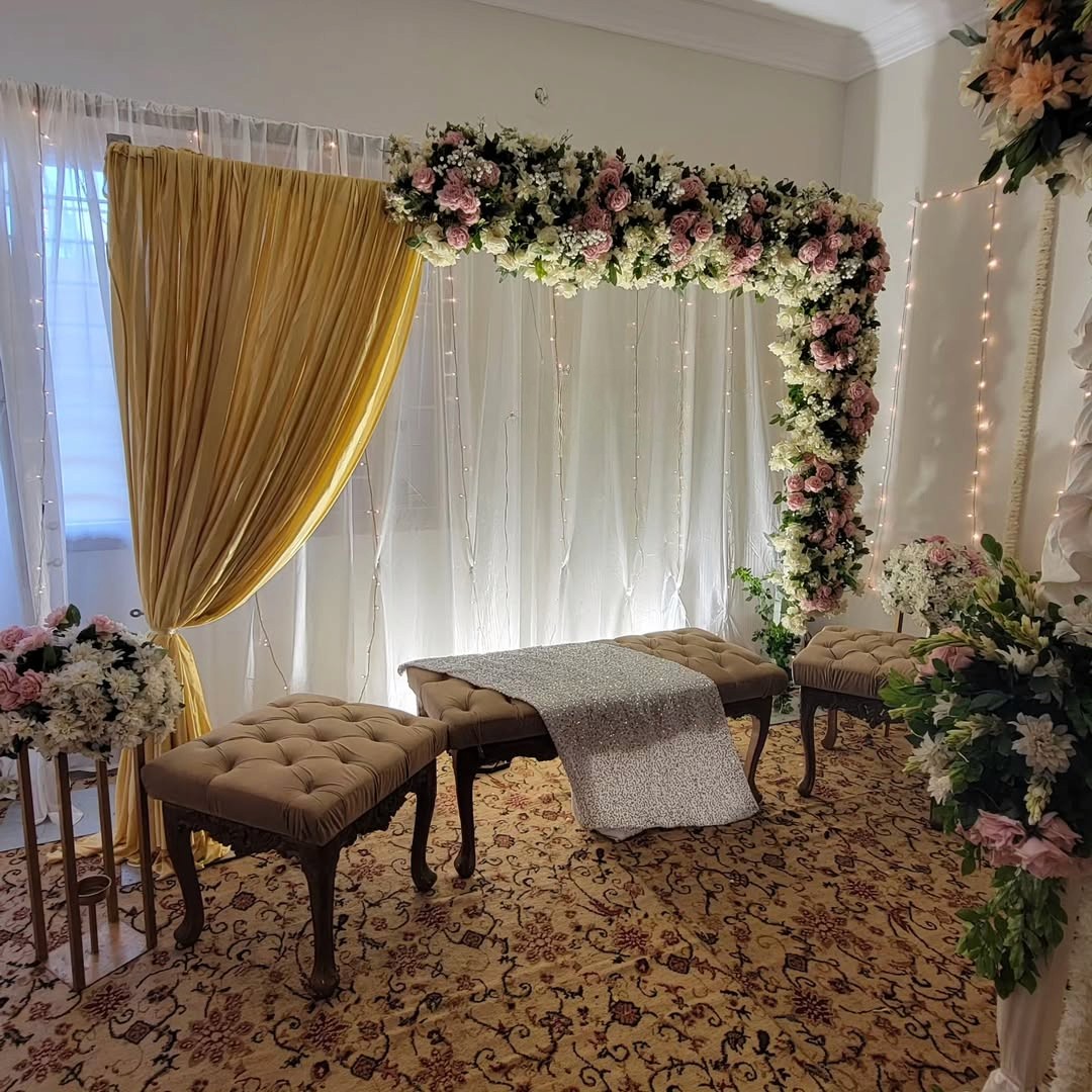 Golden drapes with white floral arch for Roka & Engagement decoration at home by Decori, Best Roka Decorator near West Delhi.