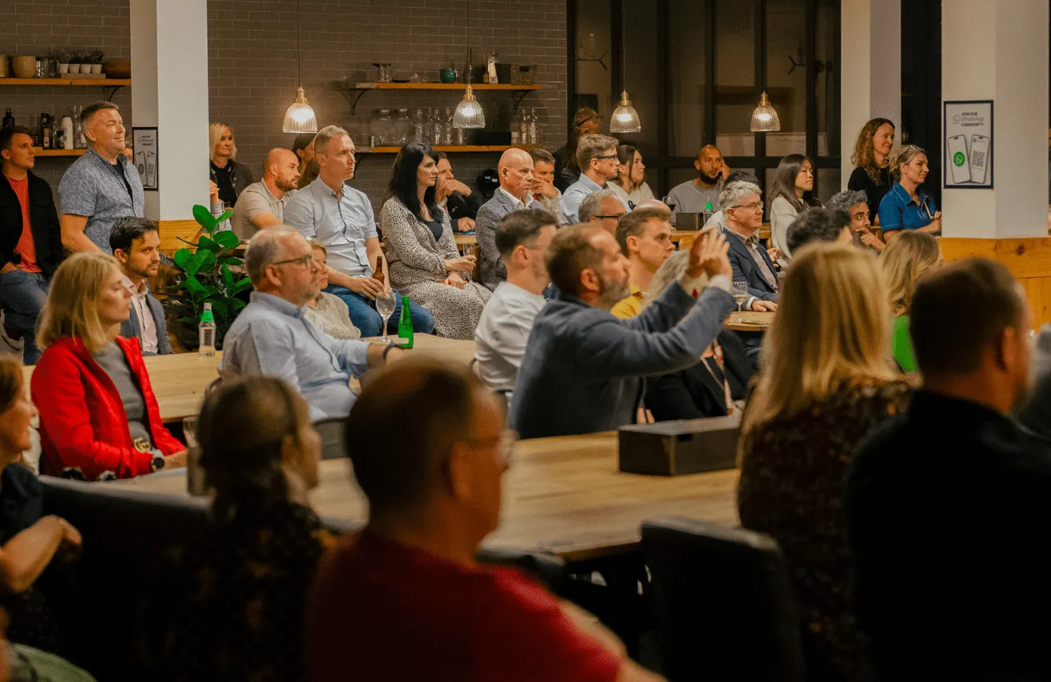 People sitting and standing in a circle at an indoor event.