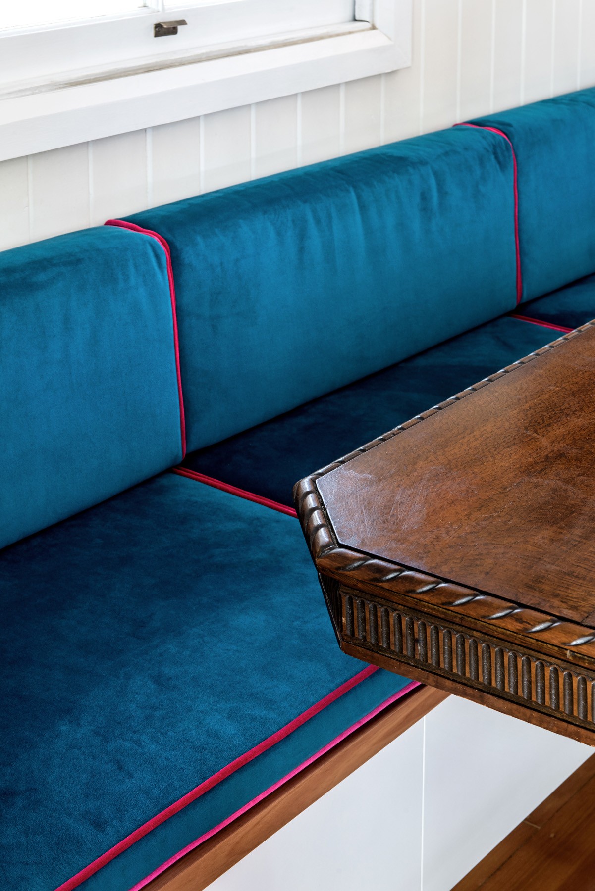 Custom upholstered bench seating at Oxford Cottage, with deep blue fabric and fine detailing integrated into the dining nook.