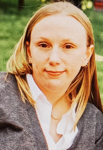 Image of a blonde woman with shoulder length hair in a white shirt and grey cardigan