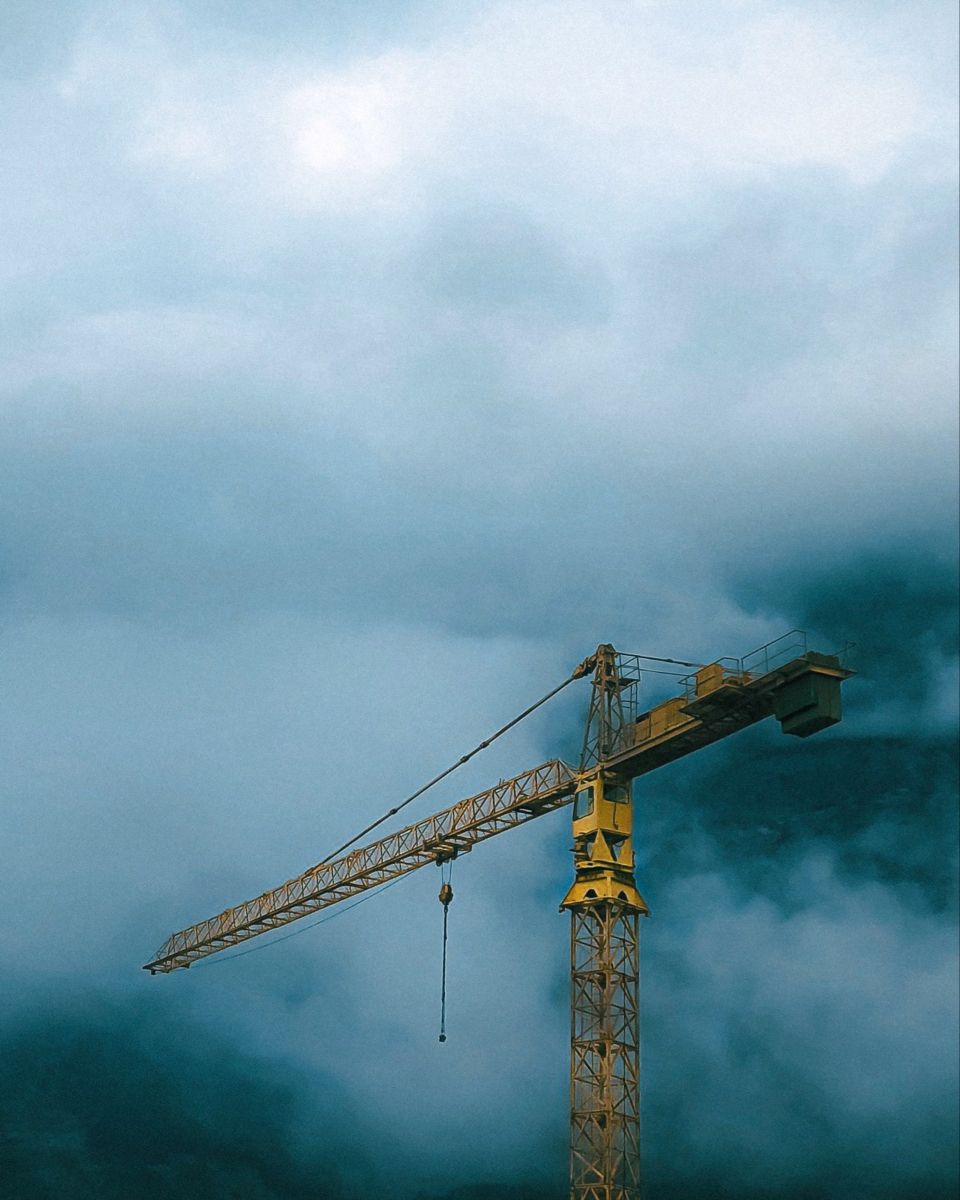 a yellow tower crane with a foggy background