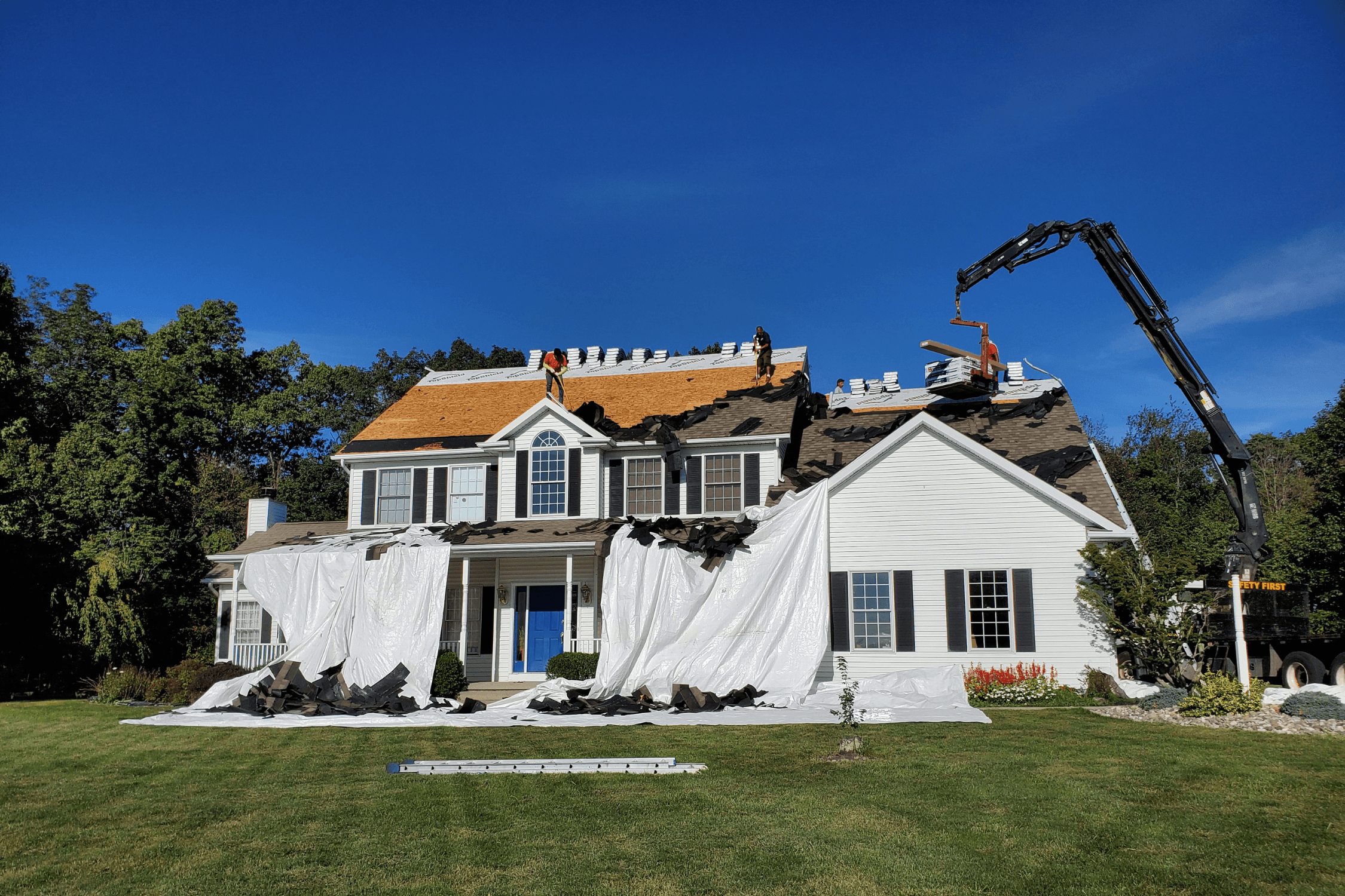 Full roof tear off with crane loading roofing materials in Shawnee, Kansas